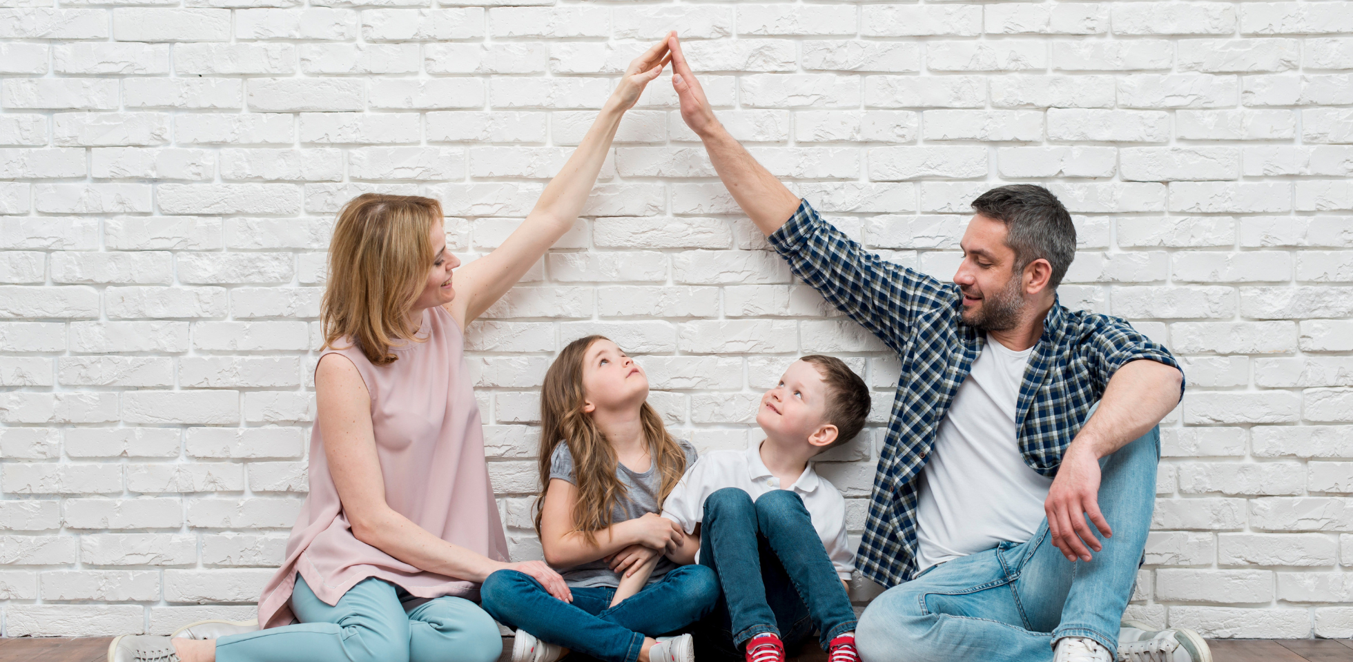 Die Eltern einer jungen Familie bilden mit ihren Armen ein schützendes Dach über ihren Kindern.