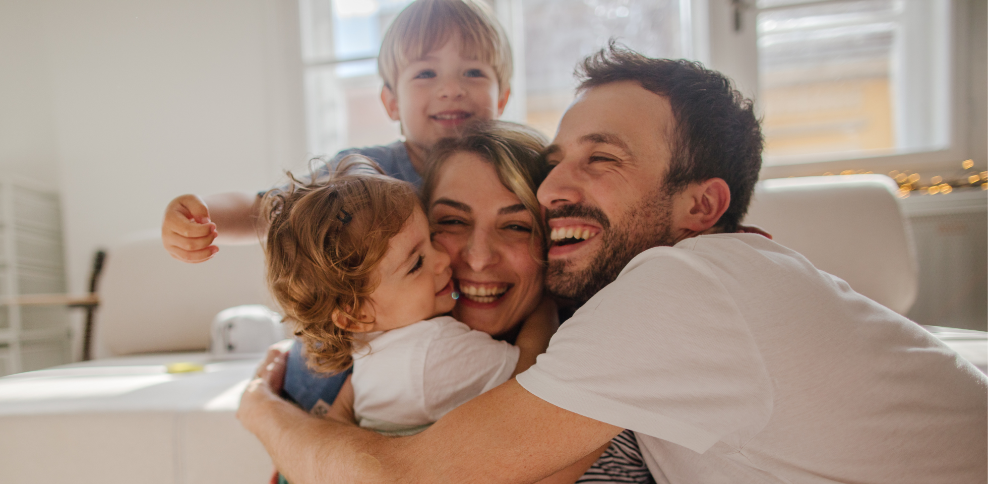 Gruppenumarmung einer jungen, vierköpfigen Familie.