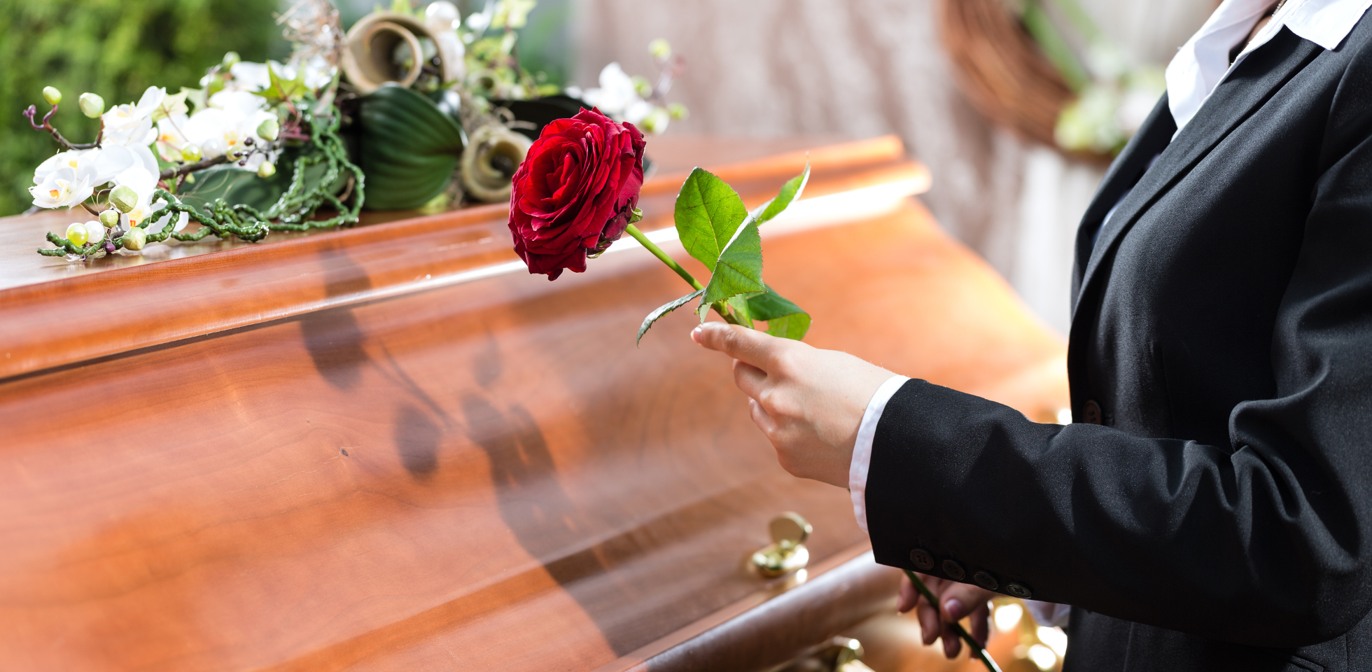 Frau legt Rose auf einen Sarg.