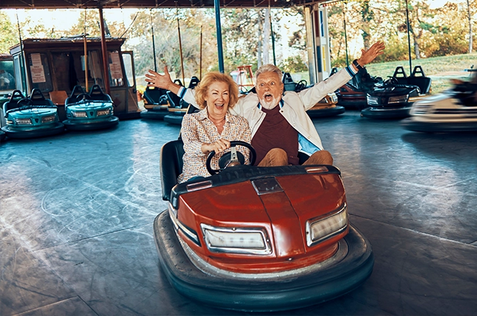 Ein fröhliches älteres Paar fährt lachend Autoscooter.