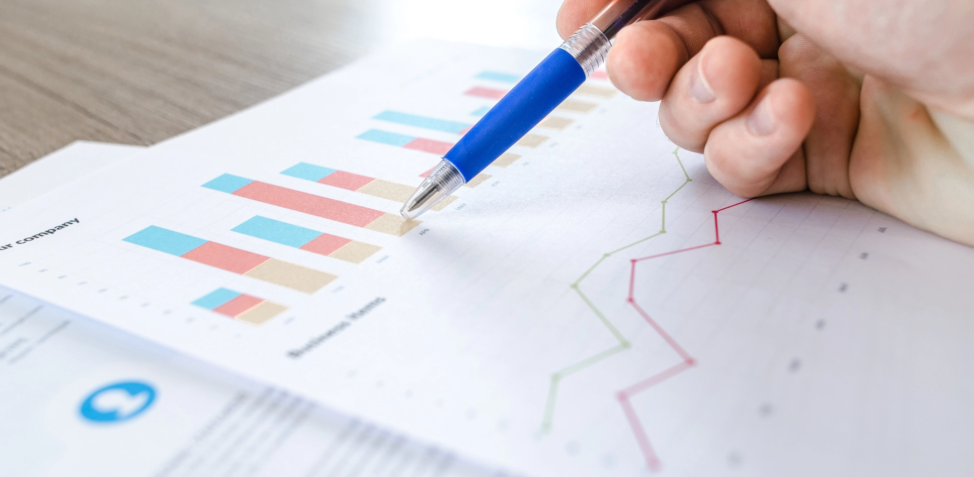 Nahaufnahme mehrerer Zettel mit Statistiken und einer Hand, die einen Stift hält.