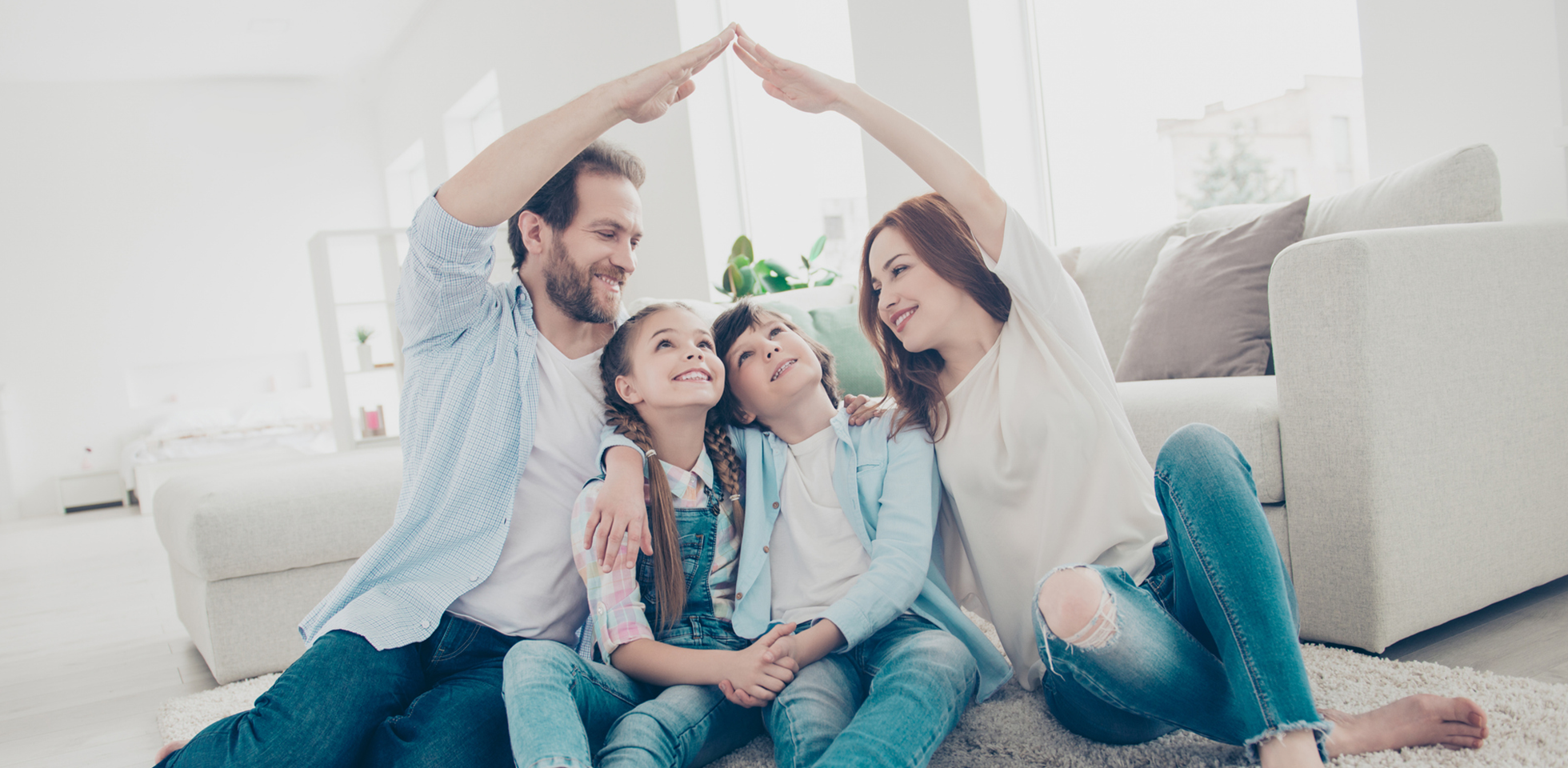 Mutter und Vater bilden mit ihren Armen ein schützendes Dach über ihren beiden Kindern.