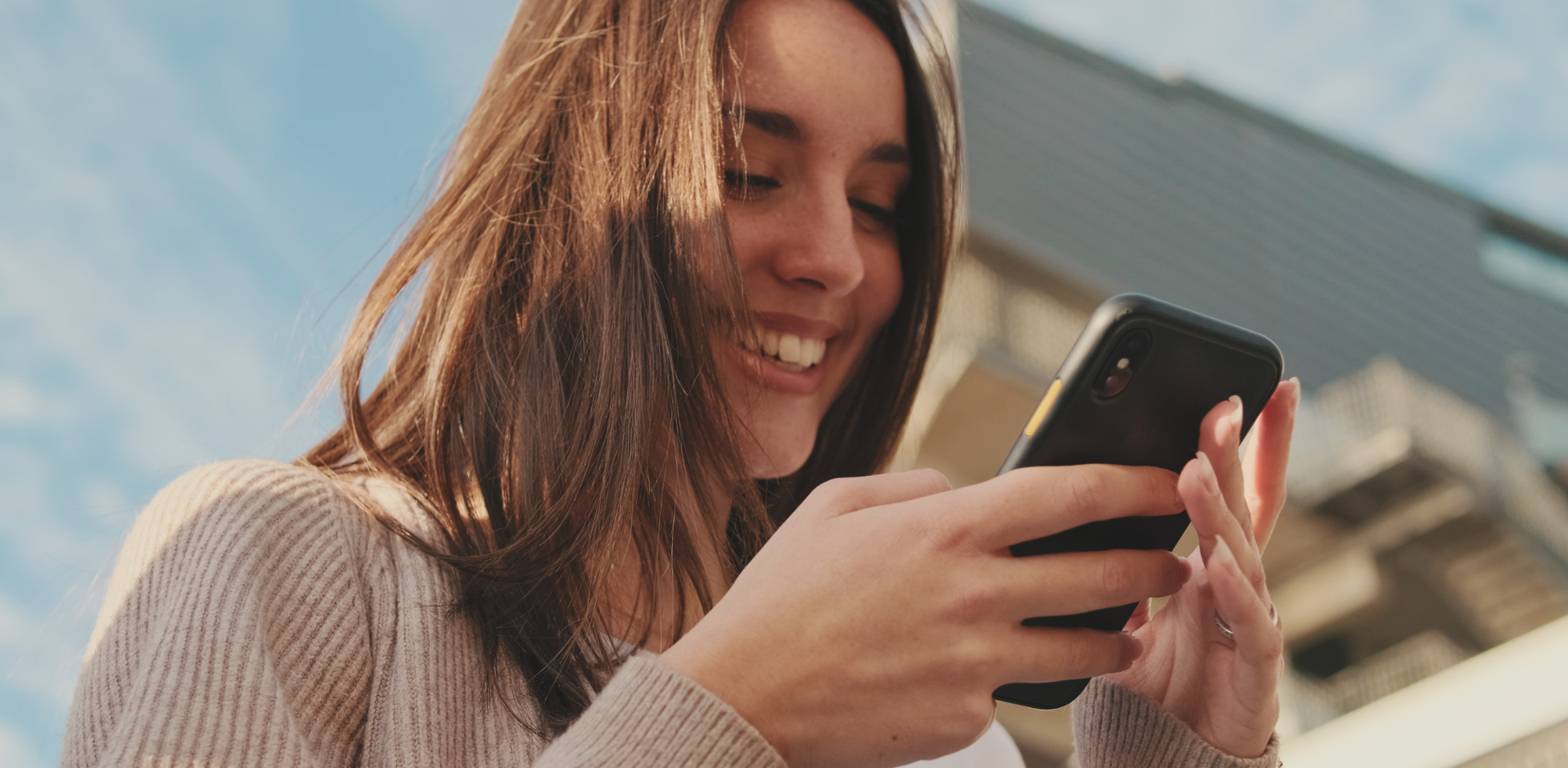 Eine junge Frau schaut auf ihr Smartphone.
